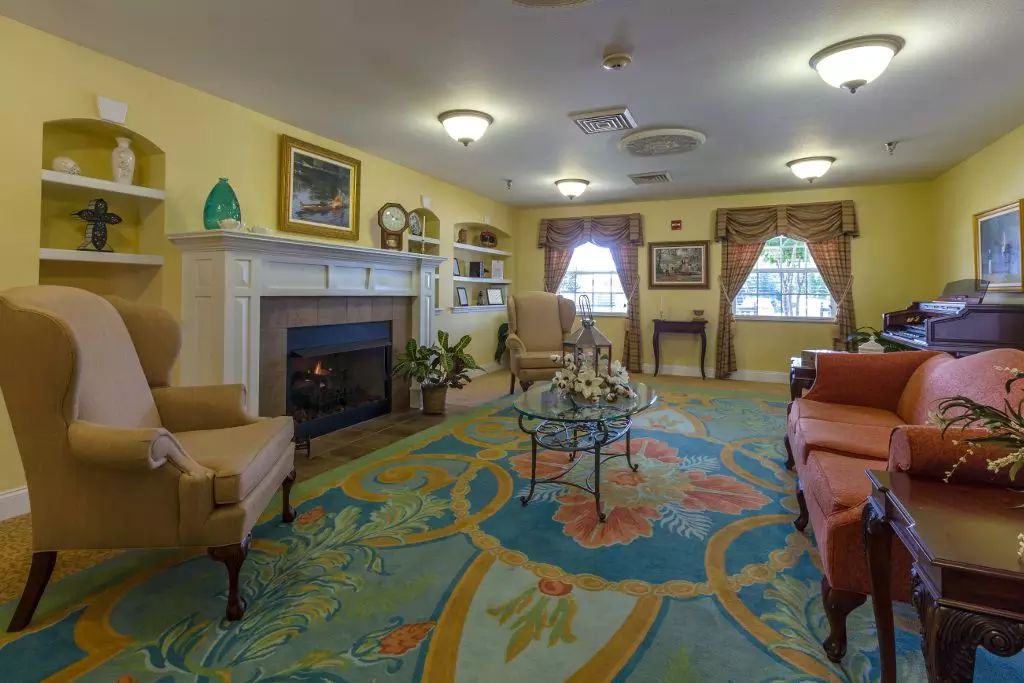 A cozy living room with tasteful furnishings, featuring a fireplace and colorful carpet.