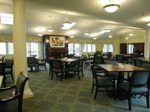 A spacious dining area with multiple tables and chairs under warm lighting.