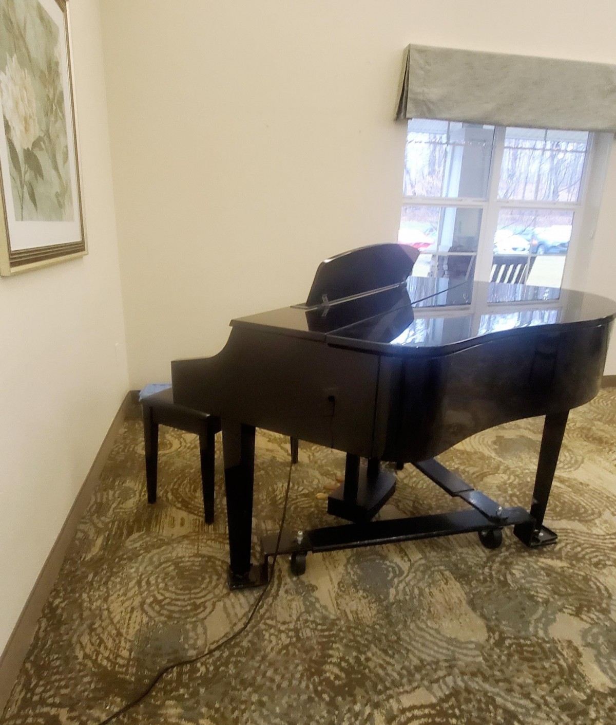 A grand piano in a well-lit room next to a window.