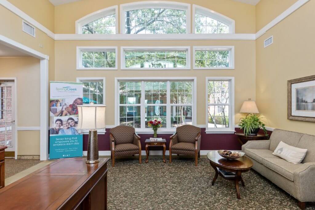 A cozy living room with large windows allowing natural light to illuminate the space, featuring comfortable seating and tasteful decor.