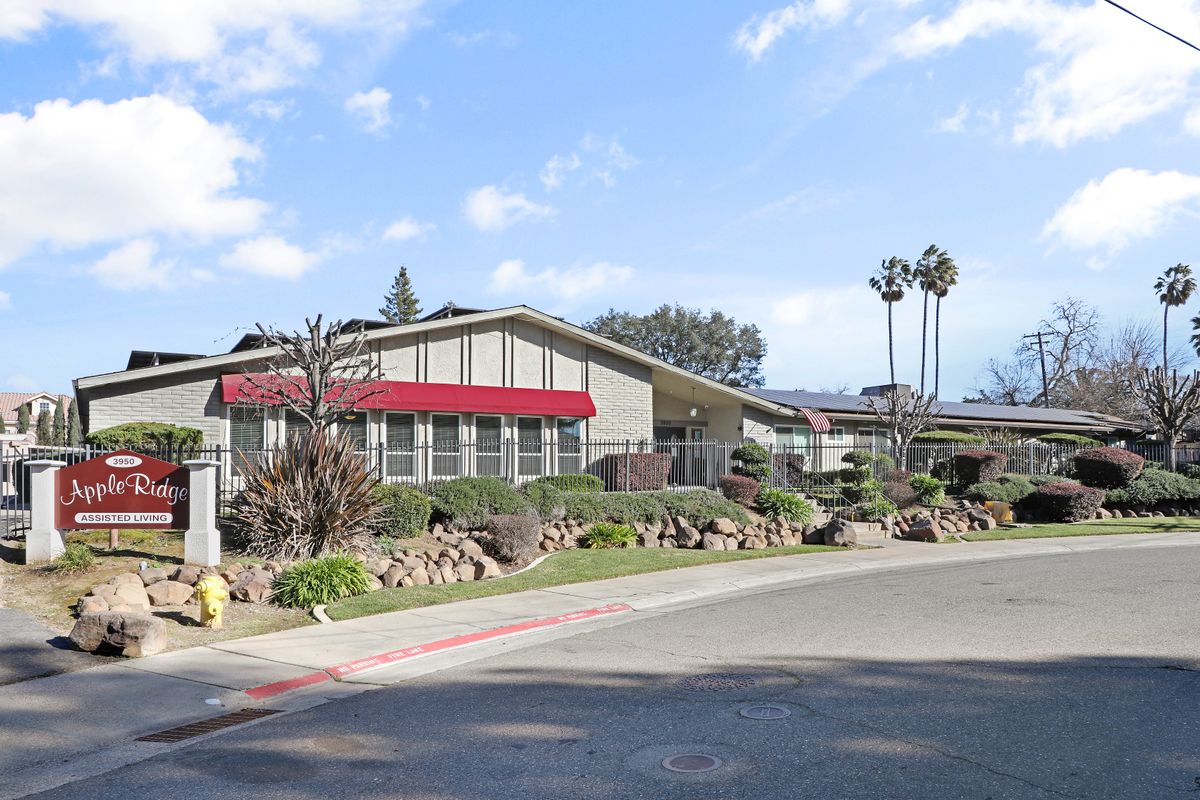 A mid-century modern building with a red awning surrounded by landscaped greenery and trees under a clear blue sky.