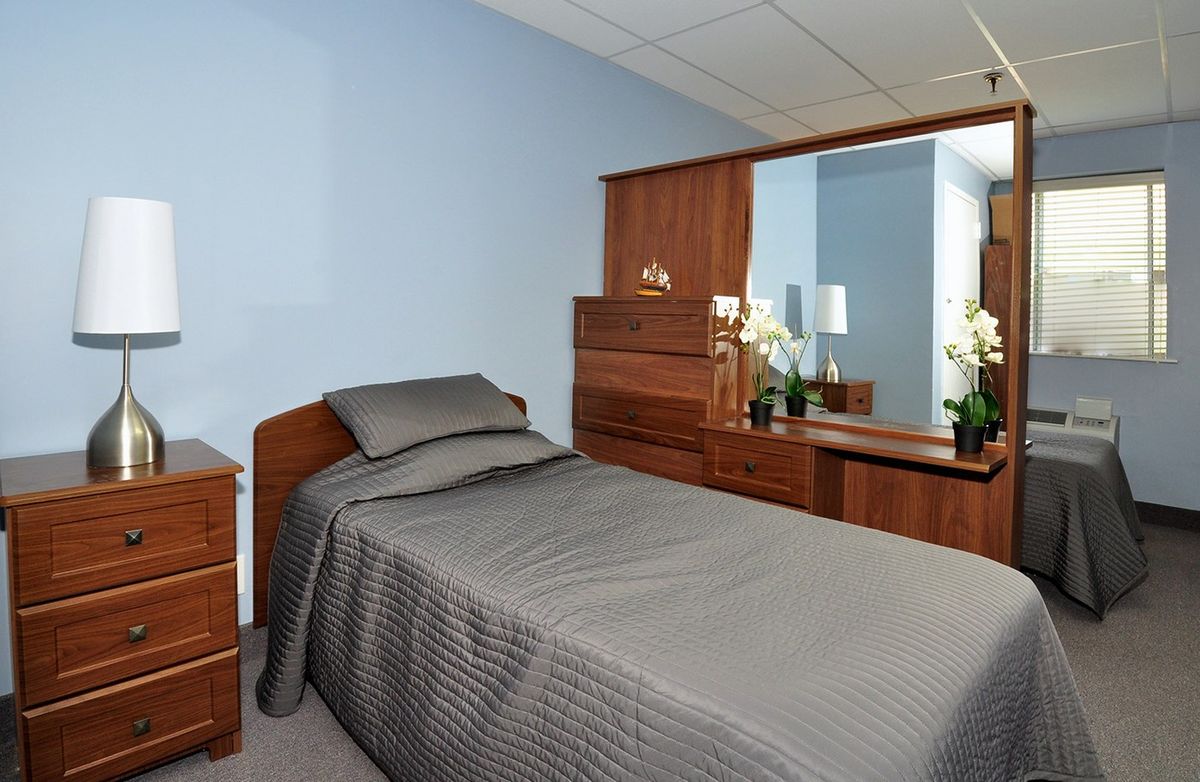 A neatly arranged bedroom with a single bed and modern wooden furniture.