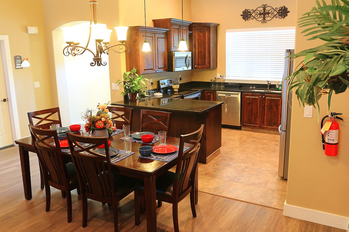 A cozy kitchen and dining area featuring wooden cabinets, modern appliances, and a neatly set dining table.