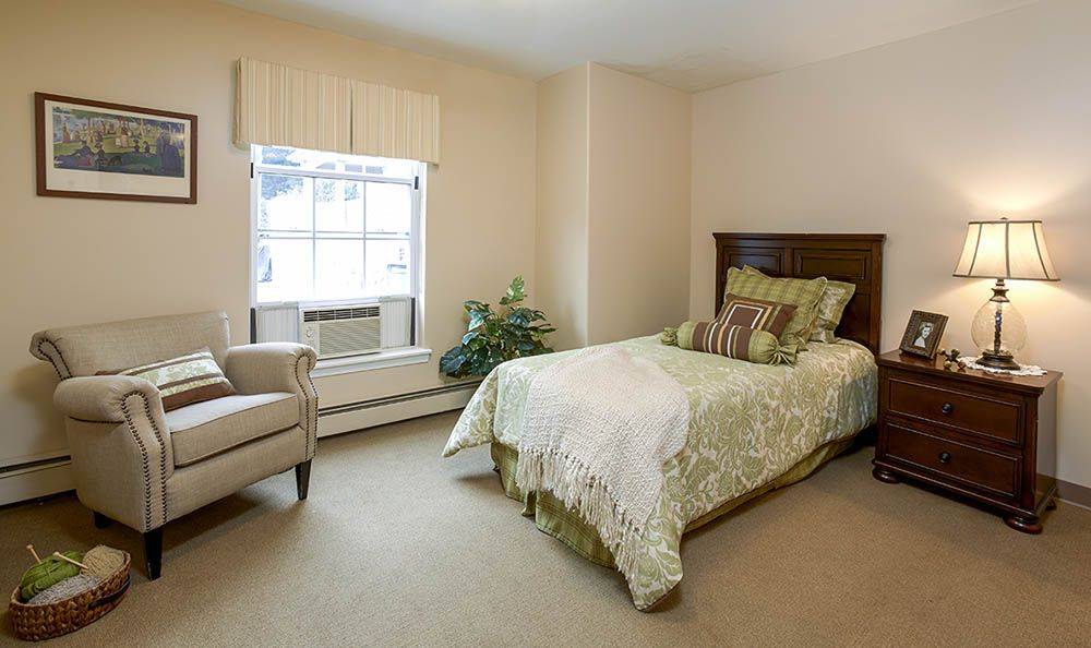 A cozy bedroom with a single bed and armchair by the window.