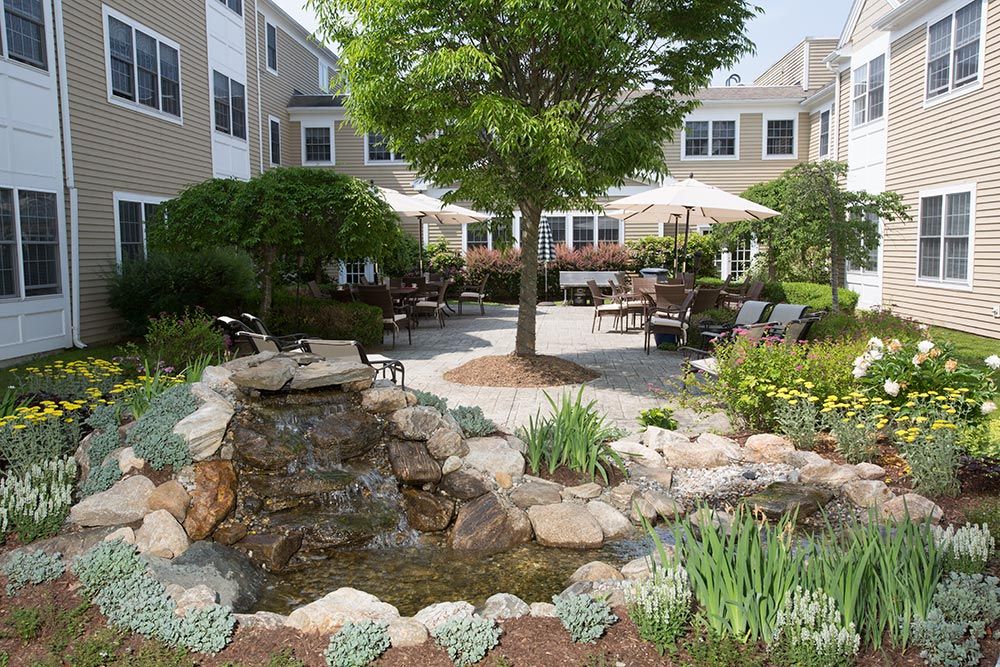 A peaceful courtyard garden with a water feature and seating areas surrounded by greenery.