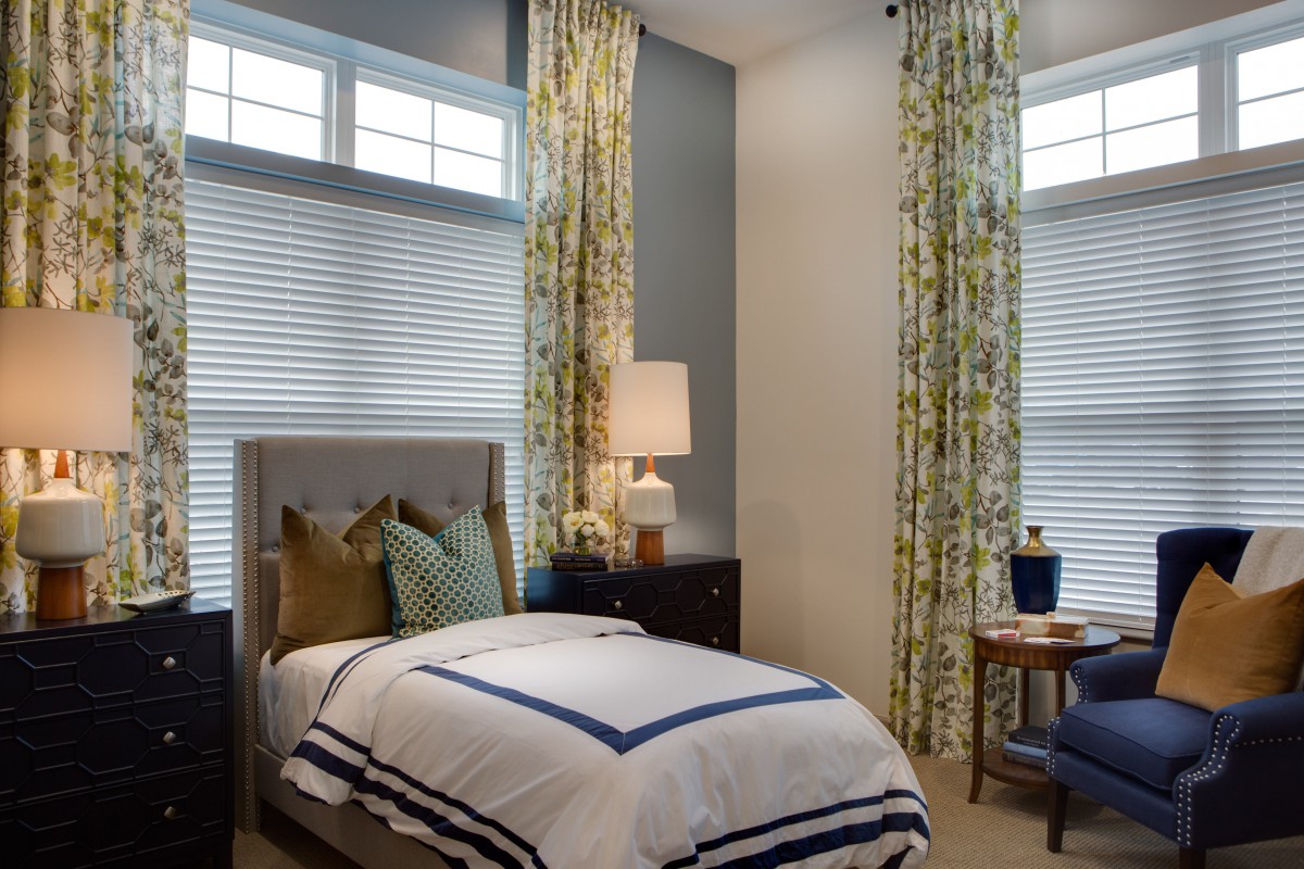A cozy bedroom with a single bed, stylish lamp, and elegant curtains.