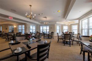 A spacious dining area with neatly arranged tables and chairs, illuminated by elegant chandeliers.