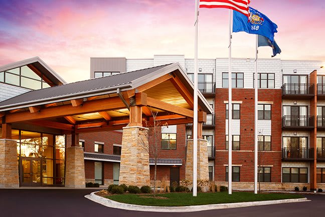 A modern hotel entrance with flags and a sunset backdrop.