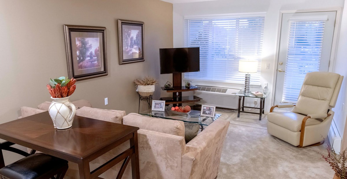 A cozy living room with a modern setup including a television, paintings on the wall, and comfortable seating.