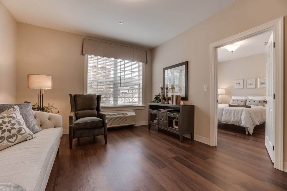 A cozy bedroom with elegant furniture and a large window, featuring hardwood flooring.