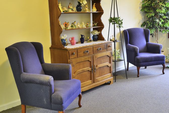 A cozy living room with vintage wooden cabinet and comfortable armchairs.