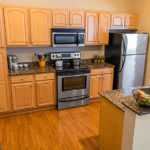 A modern kitchen with wooden cabinets, stainless steel appliances, and a granite countertop.