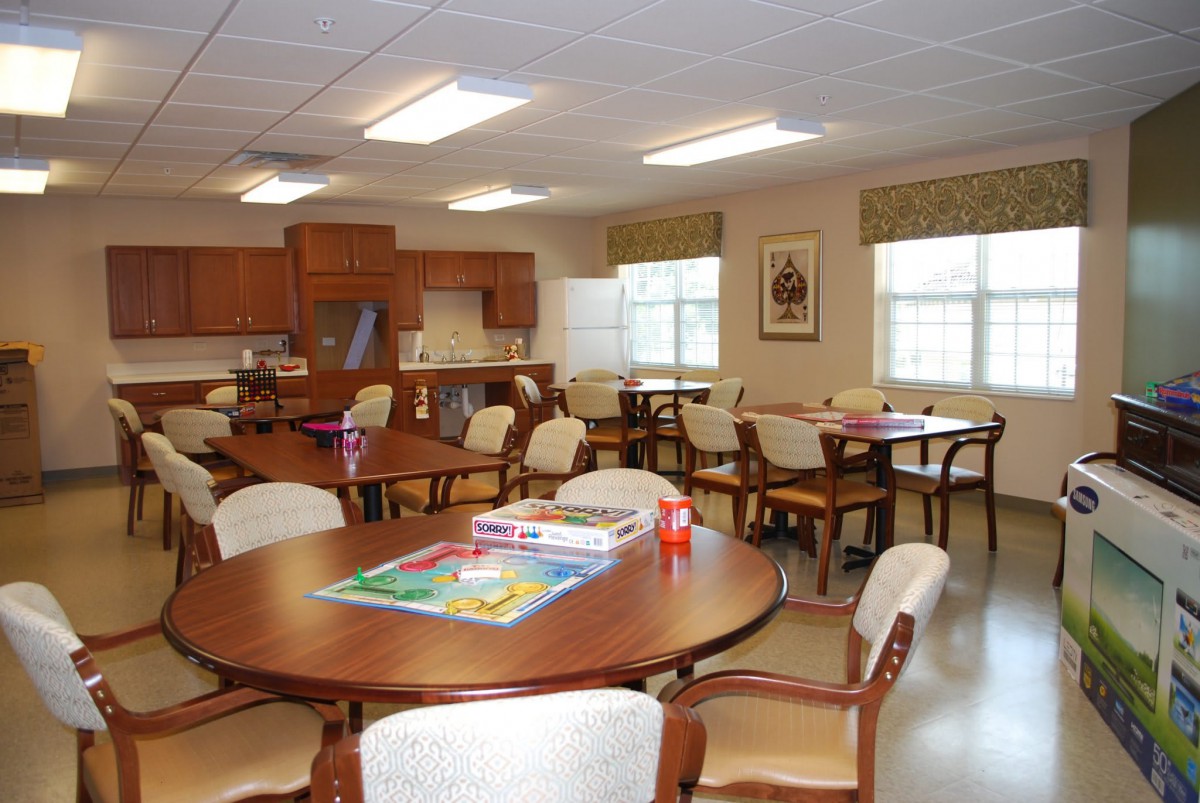 A well-lit community room with tables and chairs, featuring games on a table.