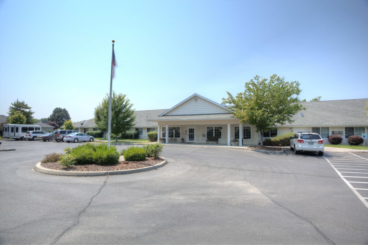 A building with a large entrance, surrounded by a parking lot and trees.