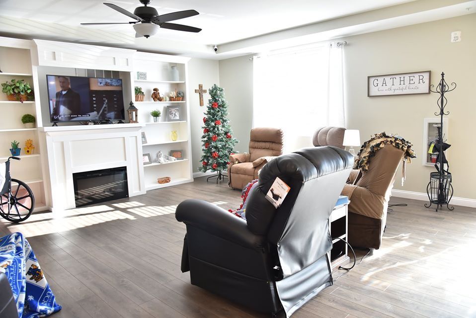 A cozy living room featuring a fireplace, recliners, and a decorated Christmas tree.