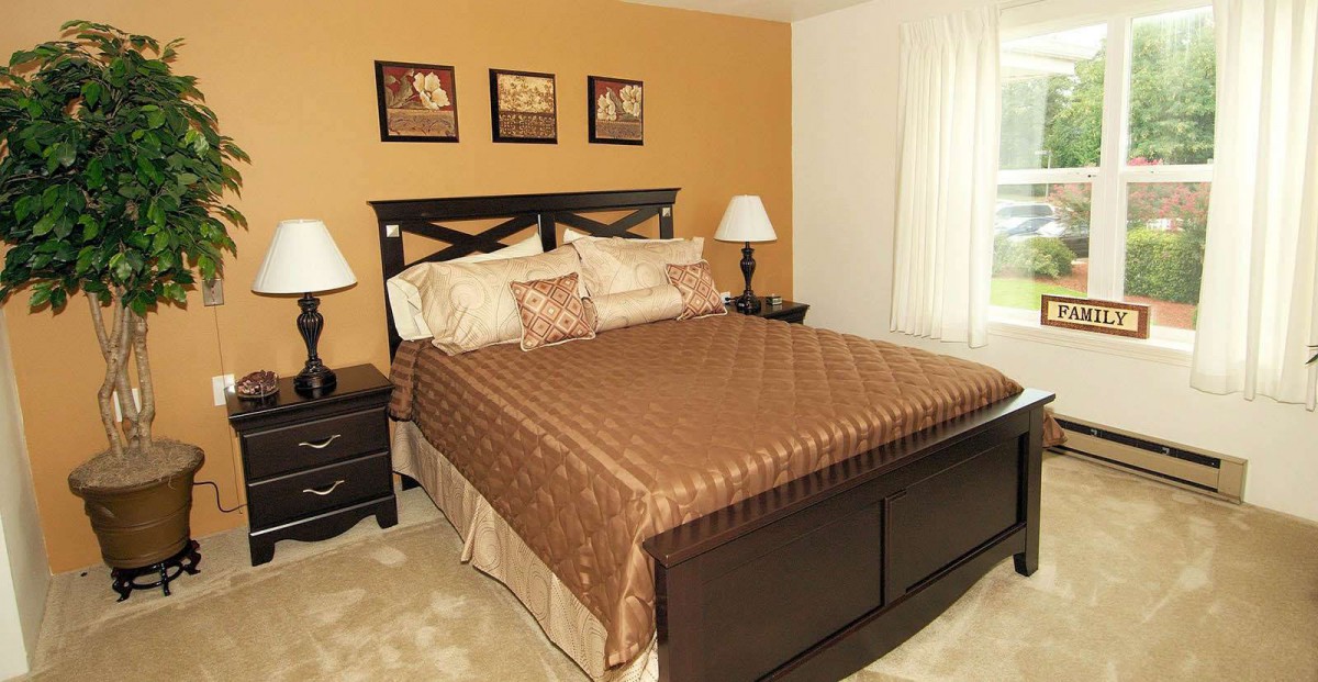 A cozy bedroom with a large bed, bedside tables and lamps, and artwork on the walls.