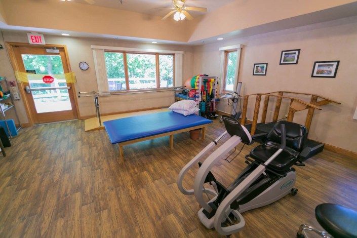 A physical therapy room equipped with exercise machines and a treatment table.