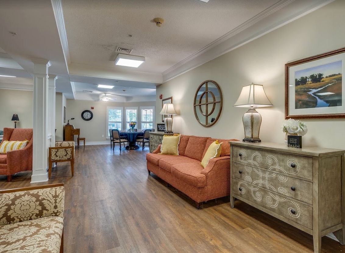 A cozy living room with a sofa and side tables, illuminated by lamps, featuring wooden floors and decorative elements.