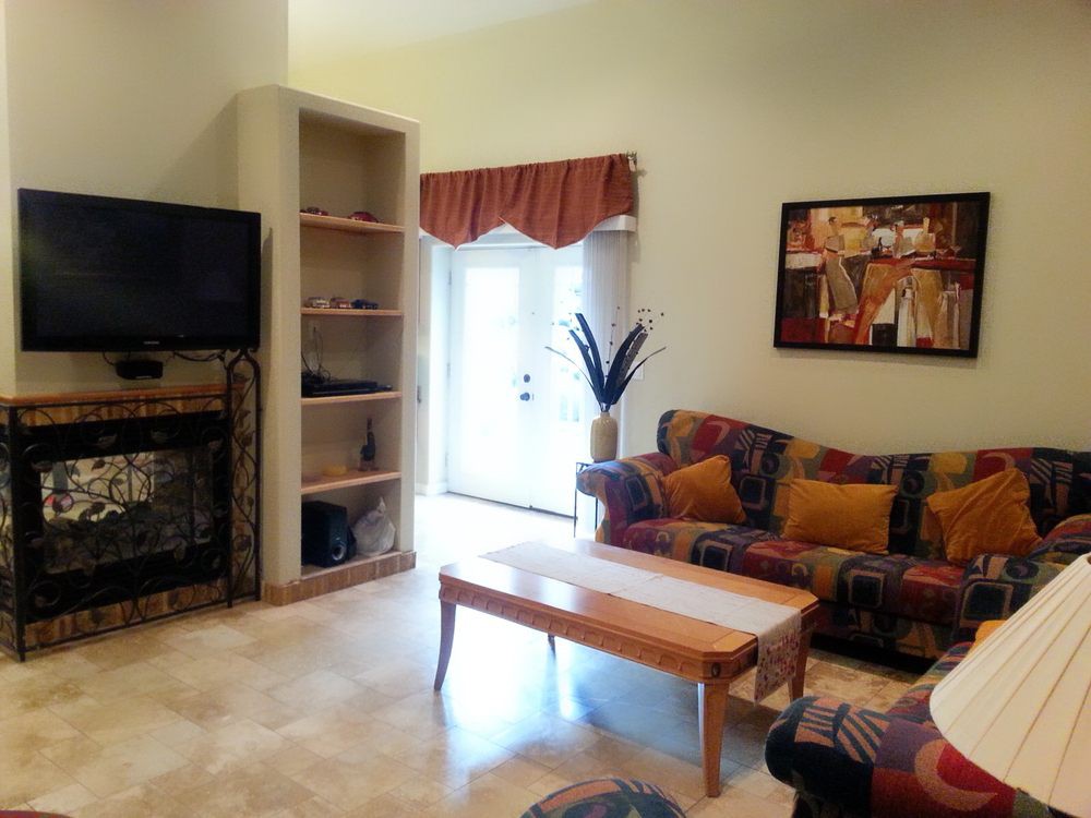 A cozy living room with a sofa, coffee table, and wall-mounted television, complemented by artwork and decorative shelves.