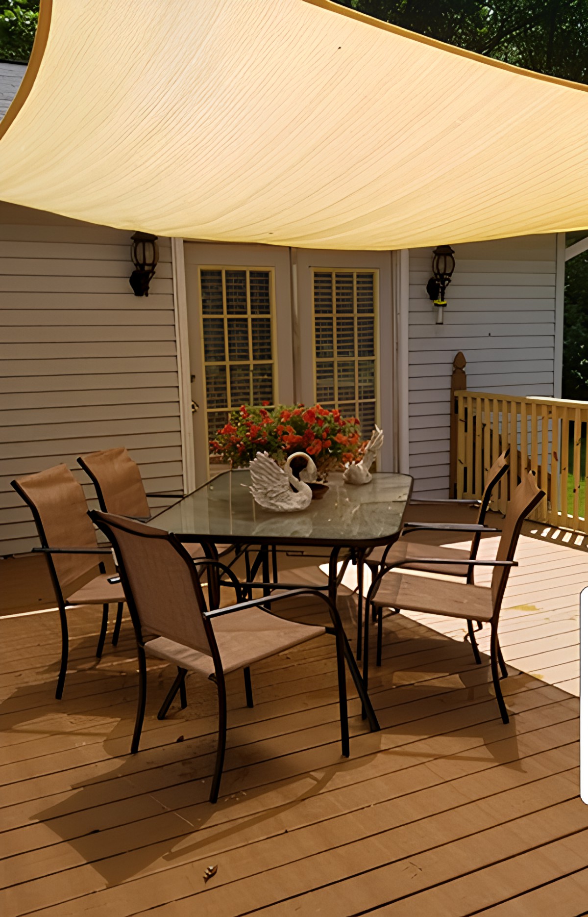 A cozy outdoor patio setup with a table and chairs under a shade sail.