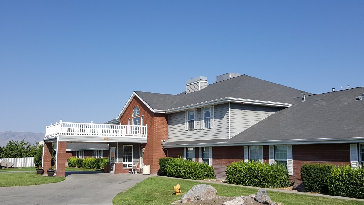 A suburban residential house with a well-maintained lawn and clear blue sky.
