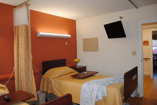 A well-organized hospital room featuring a patient bed with a tray table and a television on the wall.