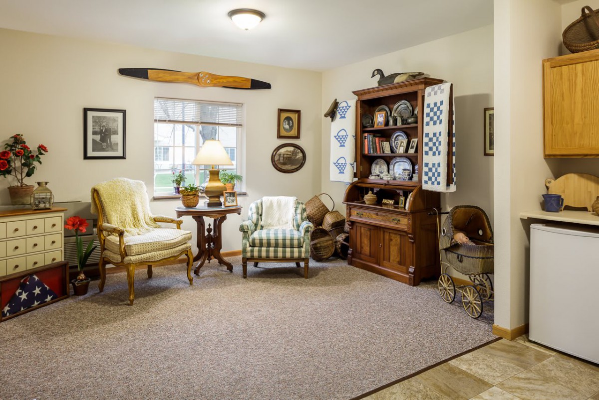 A cozy living room featuring traditional furniture and decor, with a wooden cabinet and armchairs.