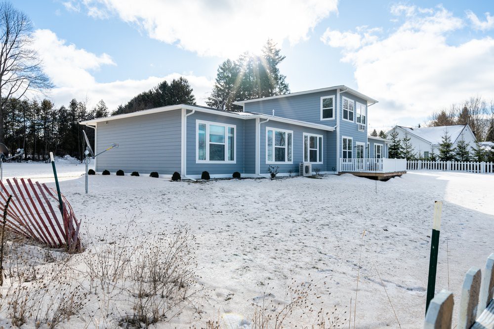 A modern house surrounded by a snowy landscape under a clear sky.