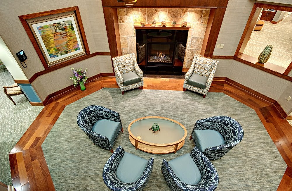 A cozy living room features a circular seating arrangement around a central table, complemented by a warm, inviting fireplace.