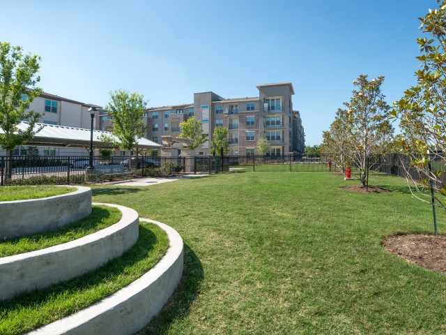 A modern building surrounded by well-maintained grass and trees, providing a pleasant outdoor space.