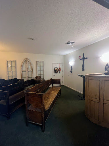 A serene interior of a church or chapel featuring wooden benches and a pulpit.