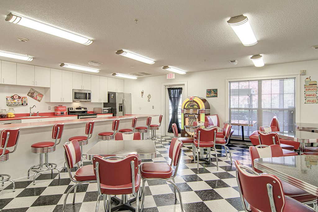 A retro-style diner with red chairs, checkered floor, and a jukebox in the corner.