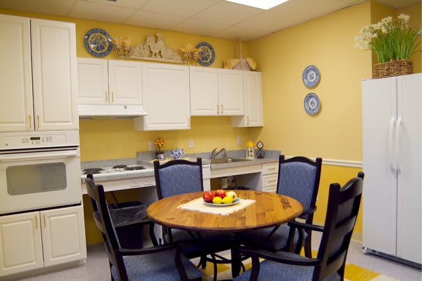 A cozy kitchen with a wooden dining table, surrounded by chairs and decorated with decorative plates on yellow walls.