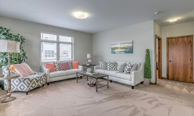 A modern living room with white sofas, a glass coffee table, and decorative accents.
