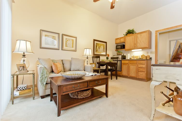 A cozy living room with an open kitchen layout, featuring comfortable furniture and warm decor.