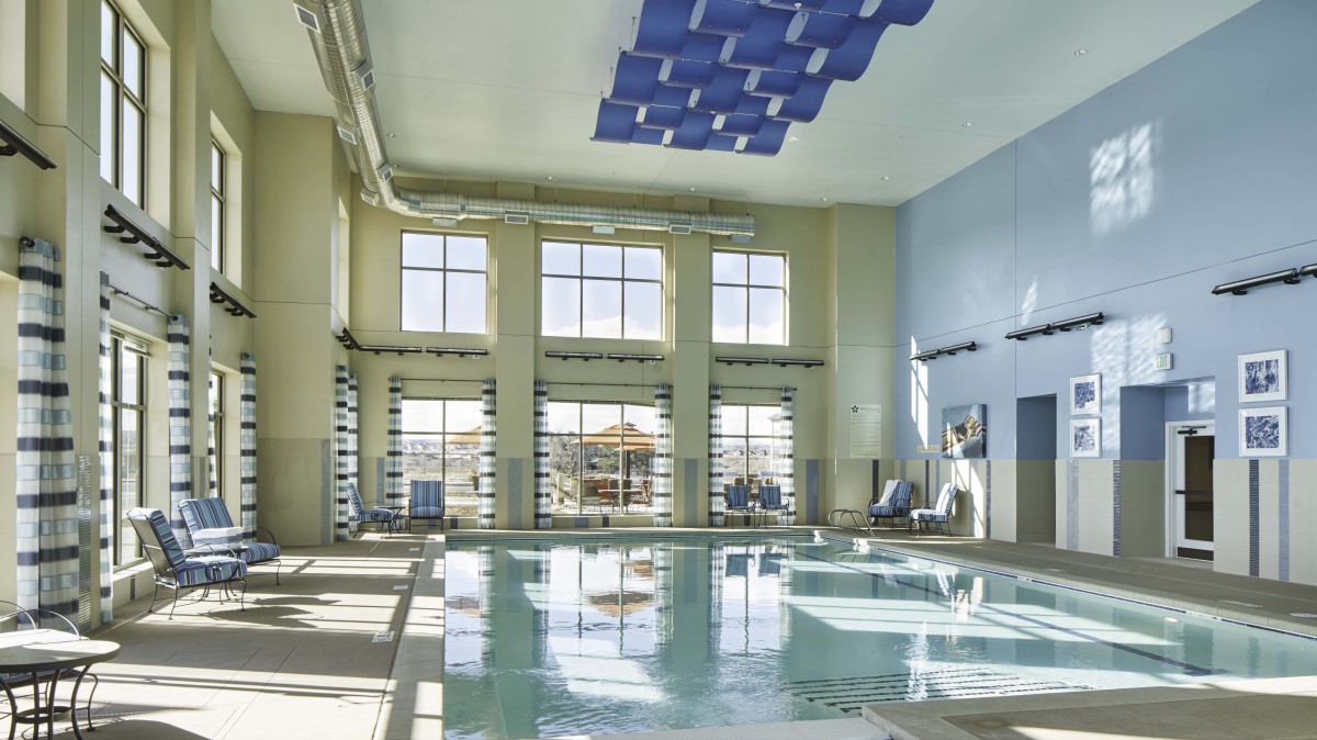 A modern indoor swimming pool with large windows allowing natural light to flood the space.
