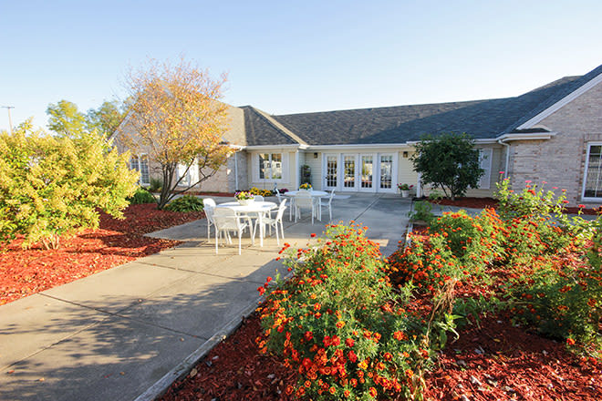 A view of a building with a landscaped garden and outdoor patio seating.