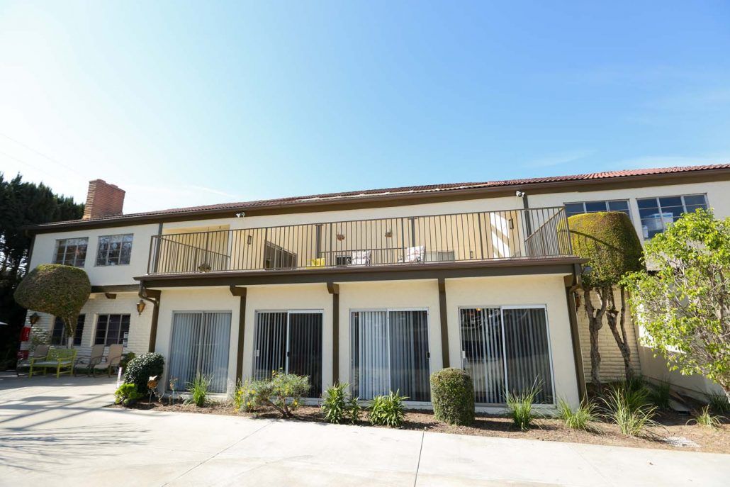 A two-story apartment building with balconies and sliding glass doors.