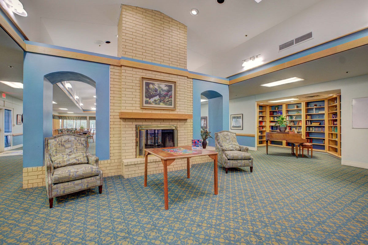 A cozy lobby area featuring a fireplace, comfortable seating, and a small library.