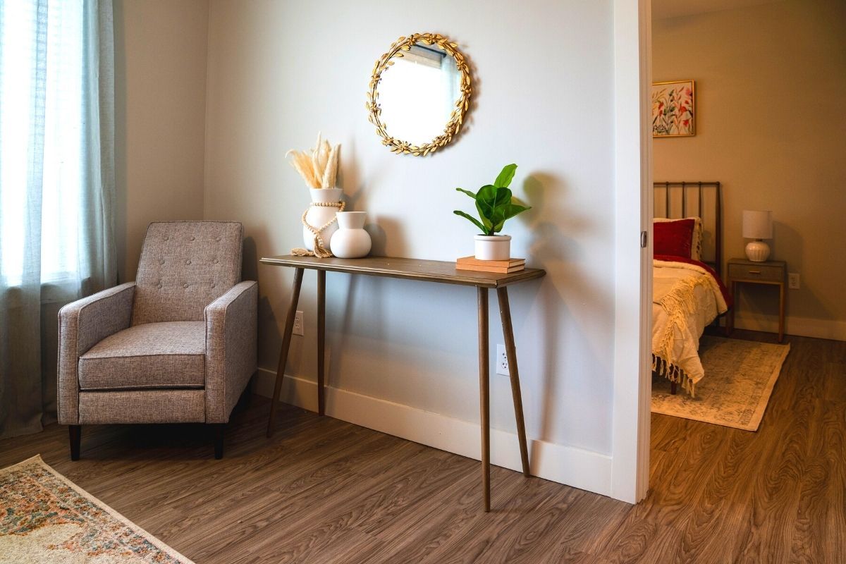 A modern living room with a console table adorned with decorative items and a wall-mounted mirror.