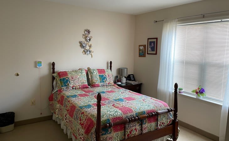 A cozy bedroom with a colorful quilt on a wooden bed frame and soft natural light filtering through the window.
