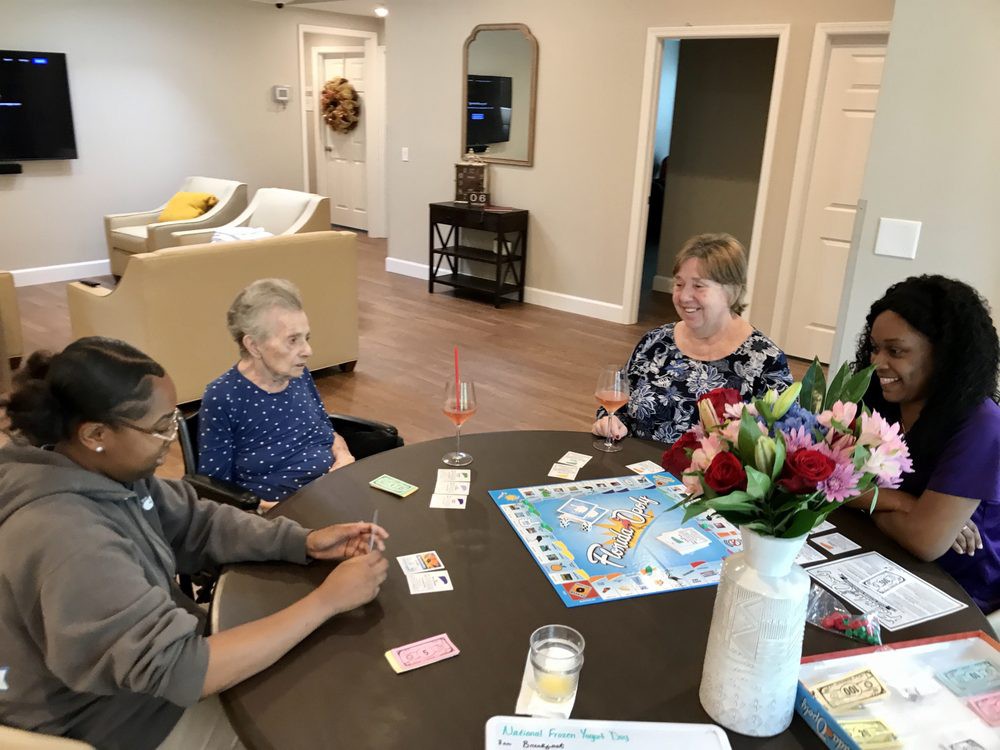 A group of people playing a board game at a table in a cozy living room.