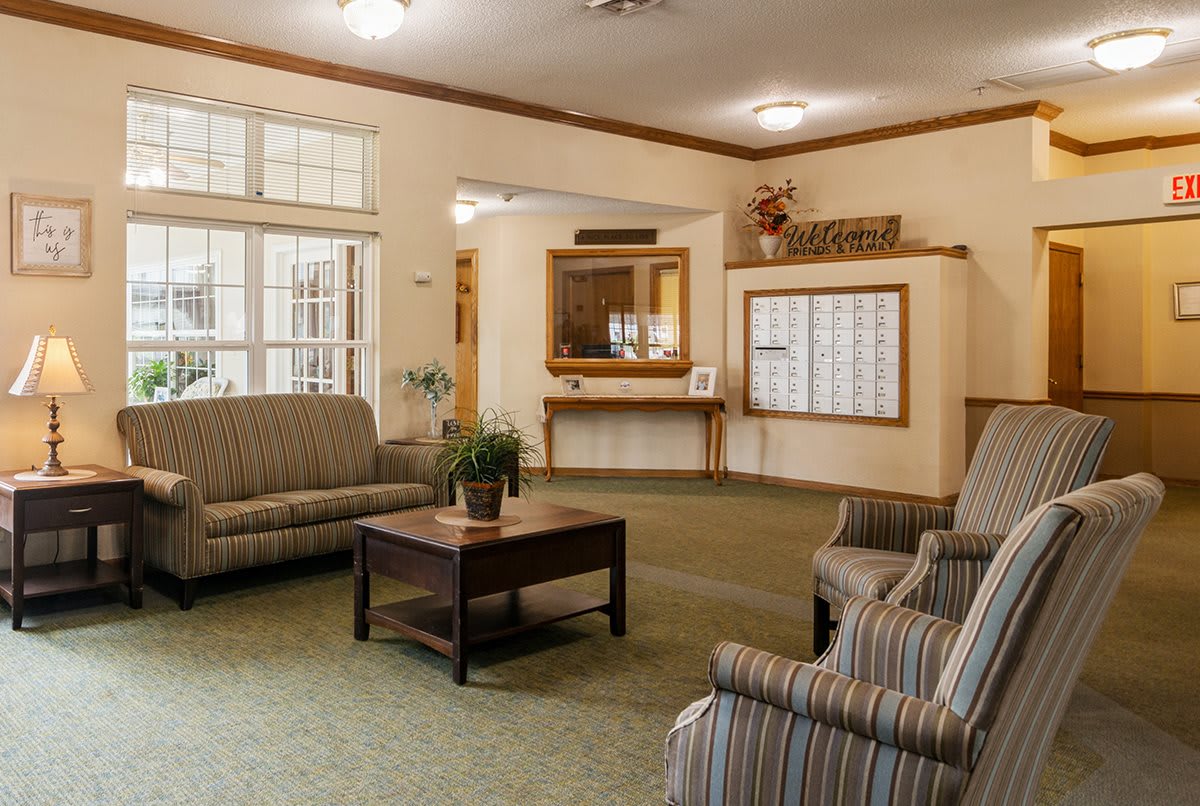 A cozy lobby featuring sofas, chairs, and a coffee table with potted plants.