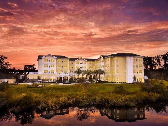 A beautiful hotel building is reflected in a serene lake at sunset.