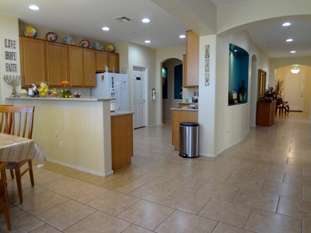 A modern kitchen with wooden cabinets and tiled flooring, featuring an open layout.