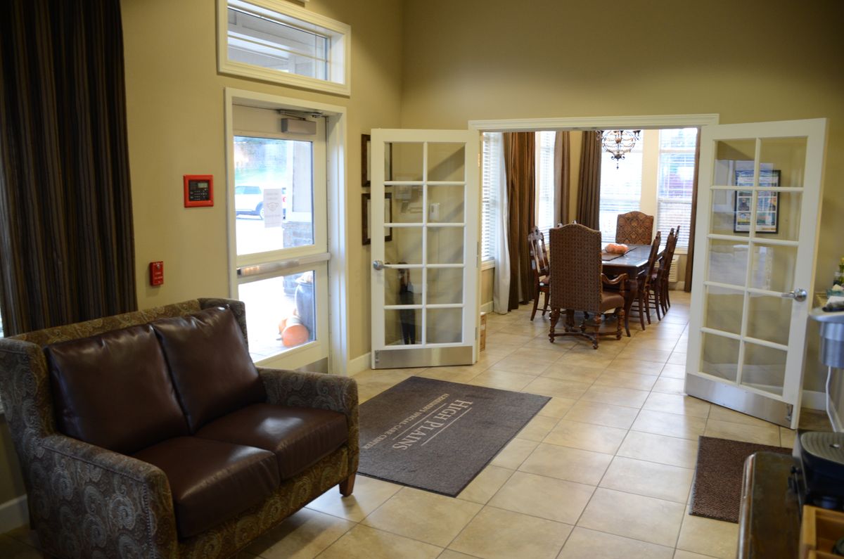 A comfortable lobby area featuring leather chairs, a table with chairs in the background, and natural lighting from large windows.