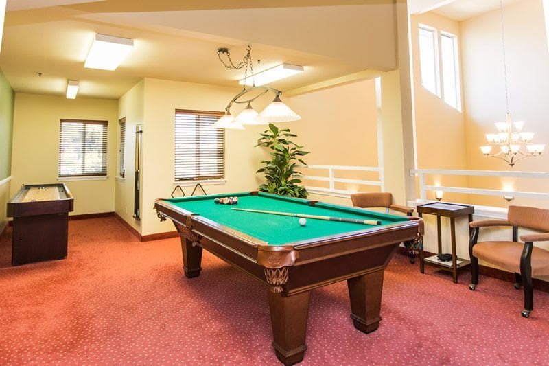 A cozy game room featuring a billiard table with green felt under bright overhead lighting.