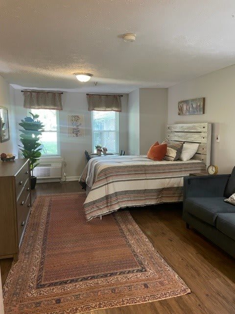 A cozy and well-decorated bedroom with a bed, sofa, and wooden flooring.
