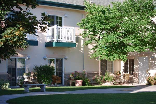 A residential building with a balcony, surrounded by trees and a well-kept lawn.