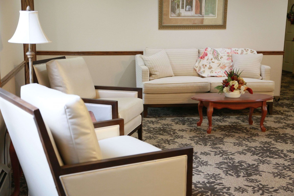 A cozy living room featuring a sofa, chairs, and a wooden coffee table with floral decor.
